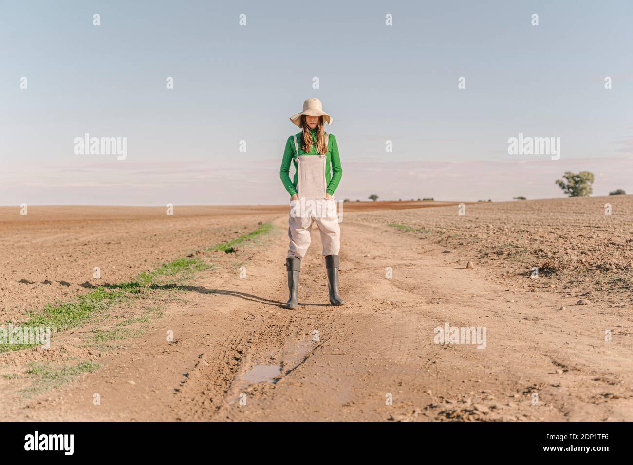 Giovane donna in piedi su campo asciutto, con le mani in tasche Foto Stock