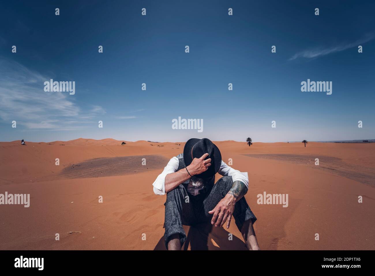 Uomo a mettere su il suo cappello nelle dune del deserto del Marocco Foto Stock