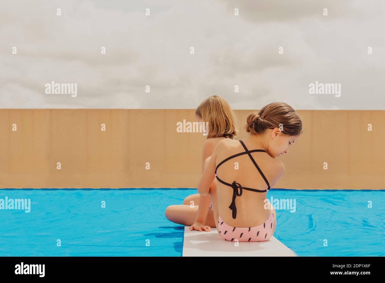 Vista posteriore di due ragazze che giocano piscina sulla terrazza sul tetto Foto Stock
