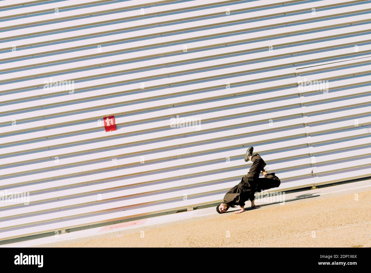 Uomo che indossa una breakdance nera di fronte all'edificio industriale Foto Stock