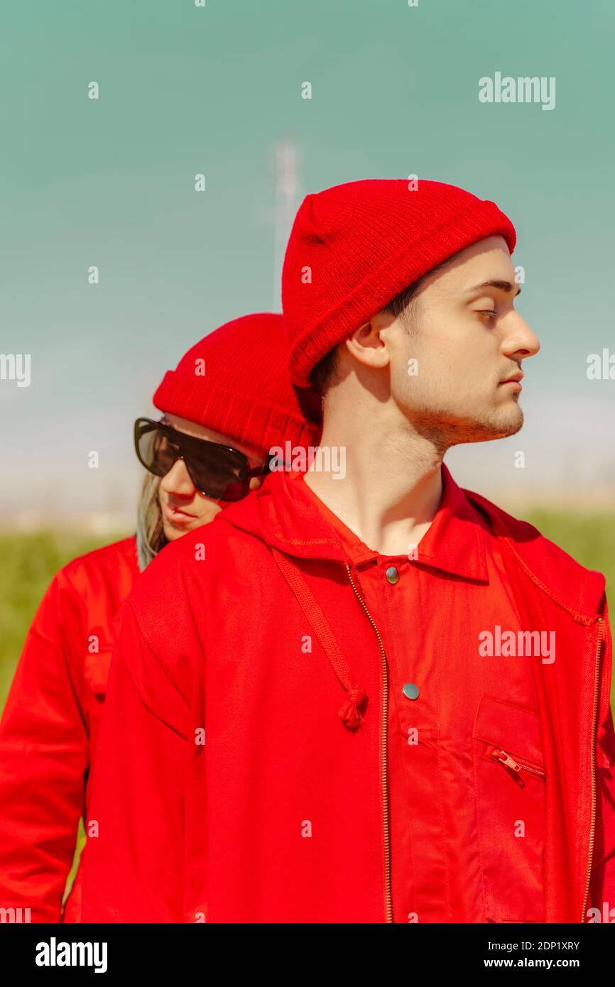 Giovane coppia con occhi chiusi vestita di rosso all'aperto Foto Stock