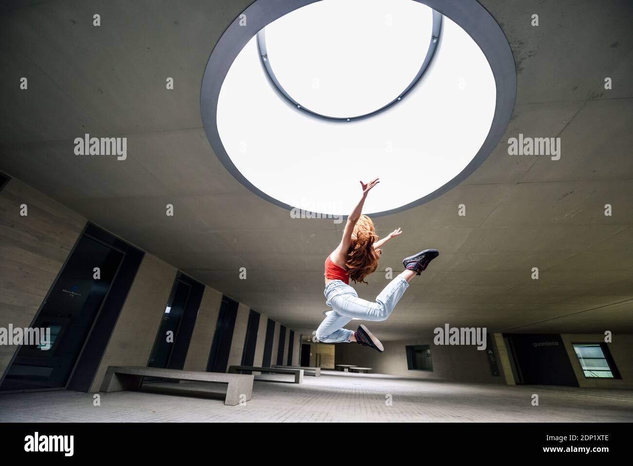 Giovane donna sportiva che salta in cortile Foto Stock