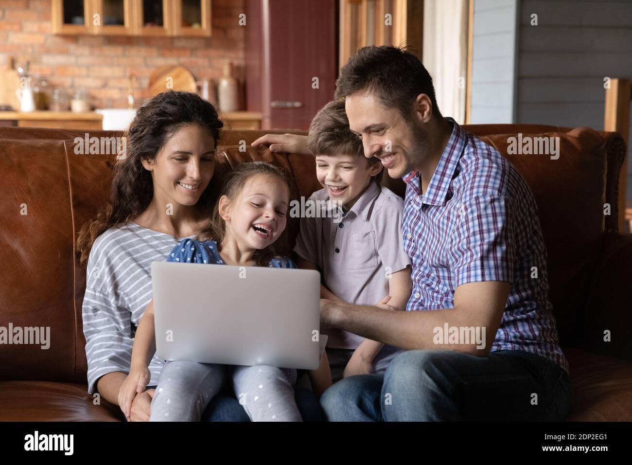 Mamma papà due bambini che abbracciano sul divano usando un PC portatile Foto Stock