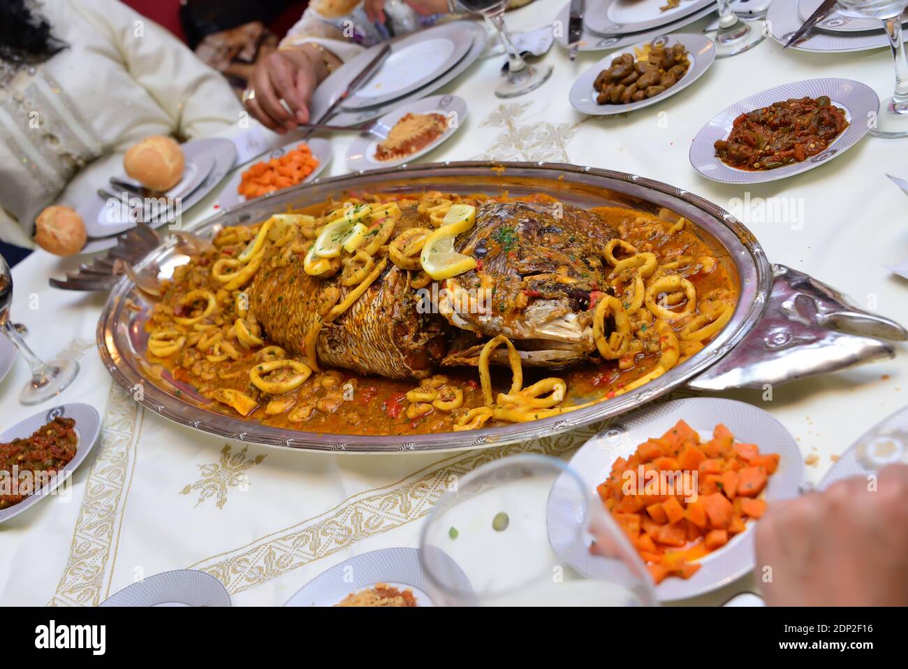 Cibo marocchino. Pesce grosso cotto con calamari tagliati. E insalate tradizionali Foto Stock