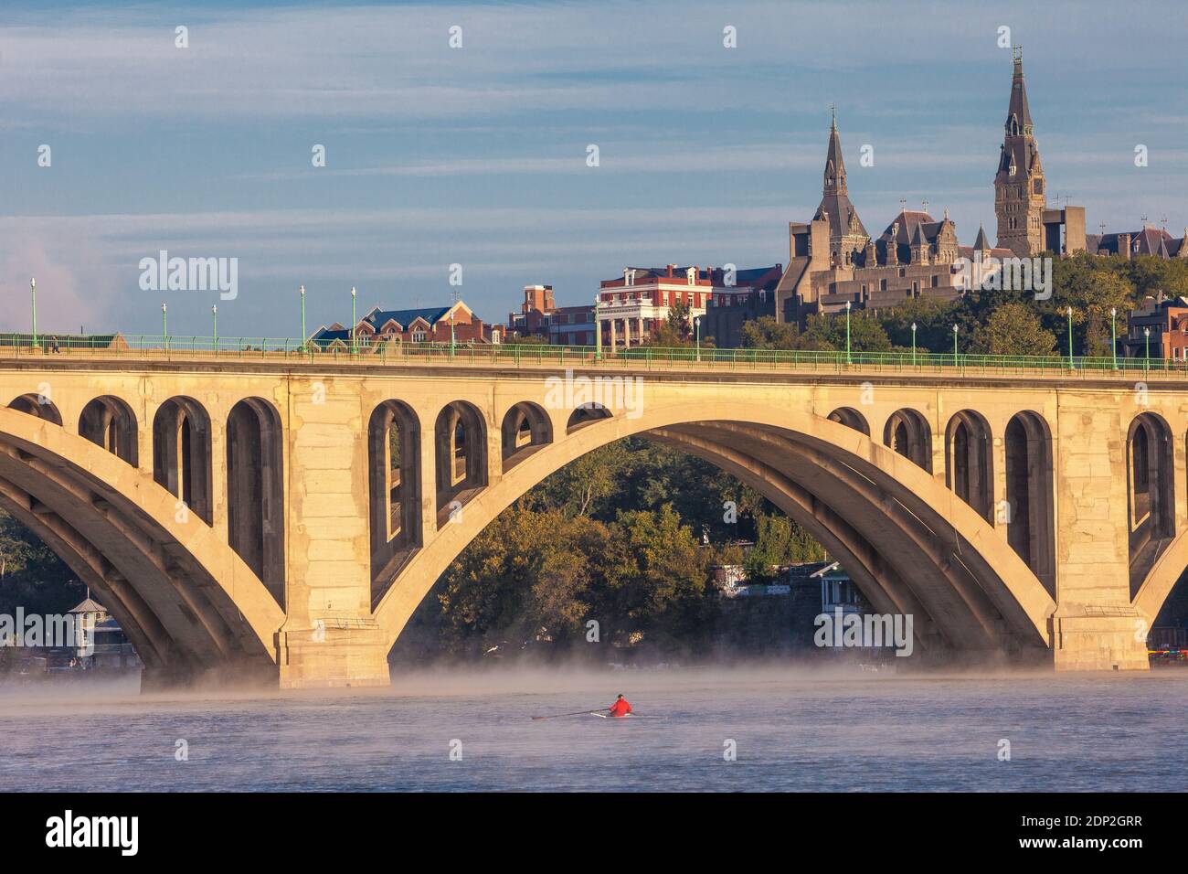 Primo mattino Rower a Skiff sul fiume Potomac, Key Bridge e Georgetown University in background, Washington DC, USA. Foto Stock