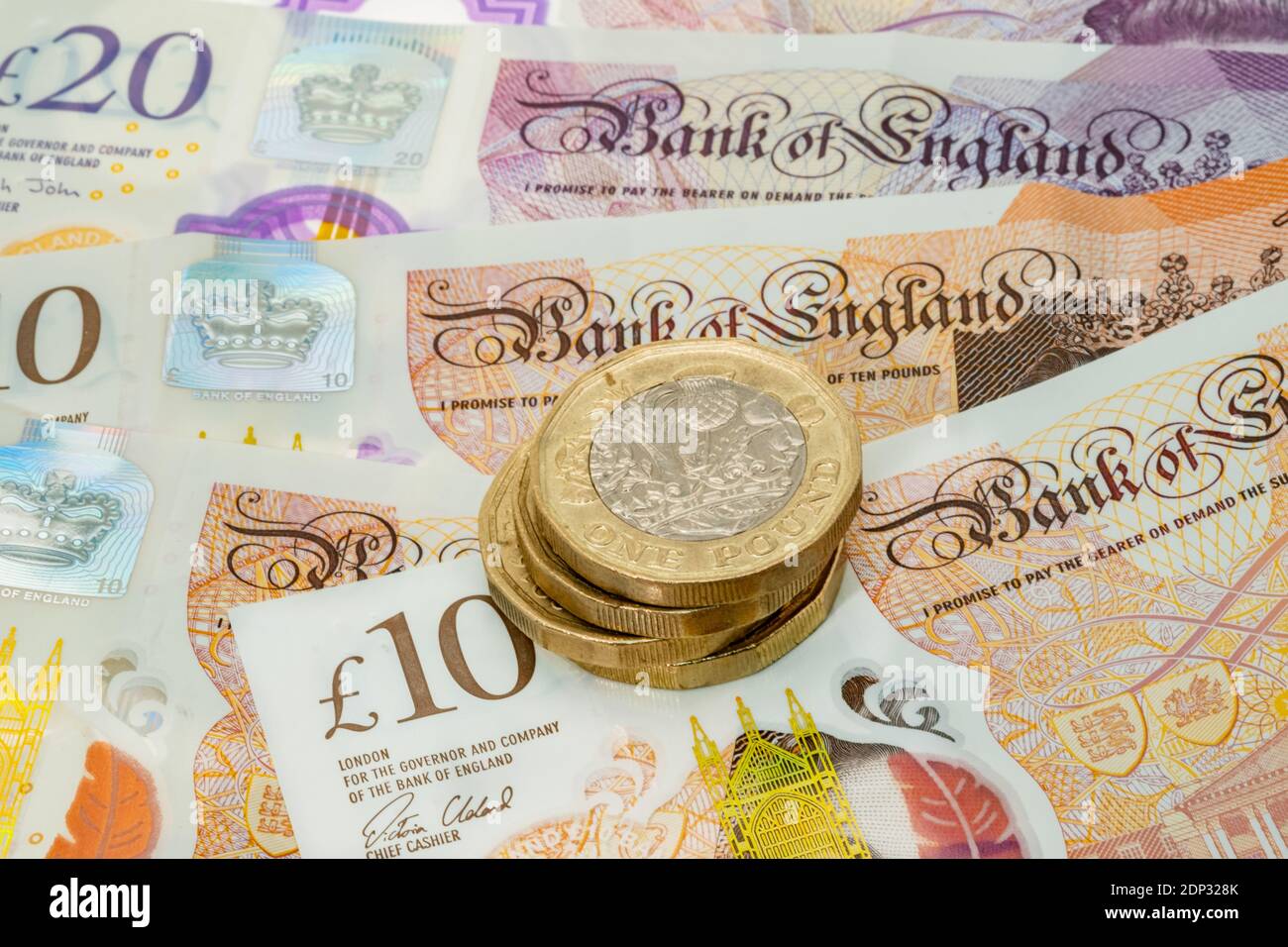 Alcune monete inglesi da una libbra poste su uno sfondo di Banconote del Regno Unito Foto Stock