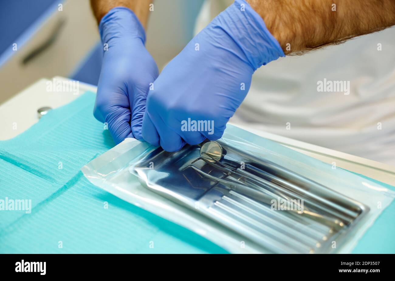 Mani di un medico che apre una sacca sterile con strumenti sterili per l'esame di un paziente Foto Stock
