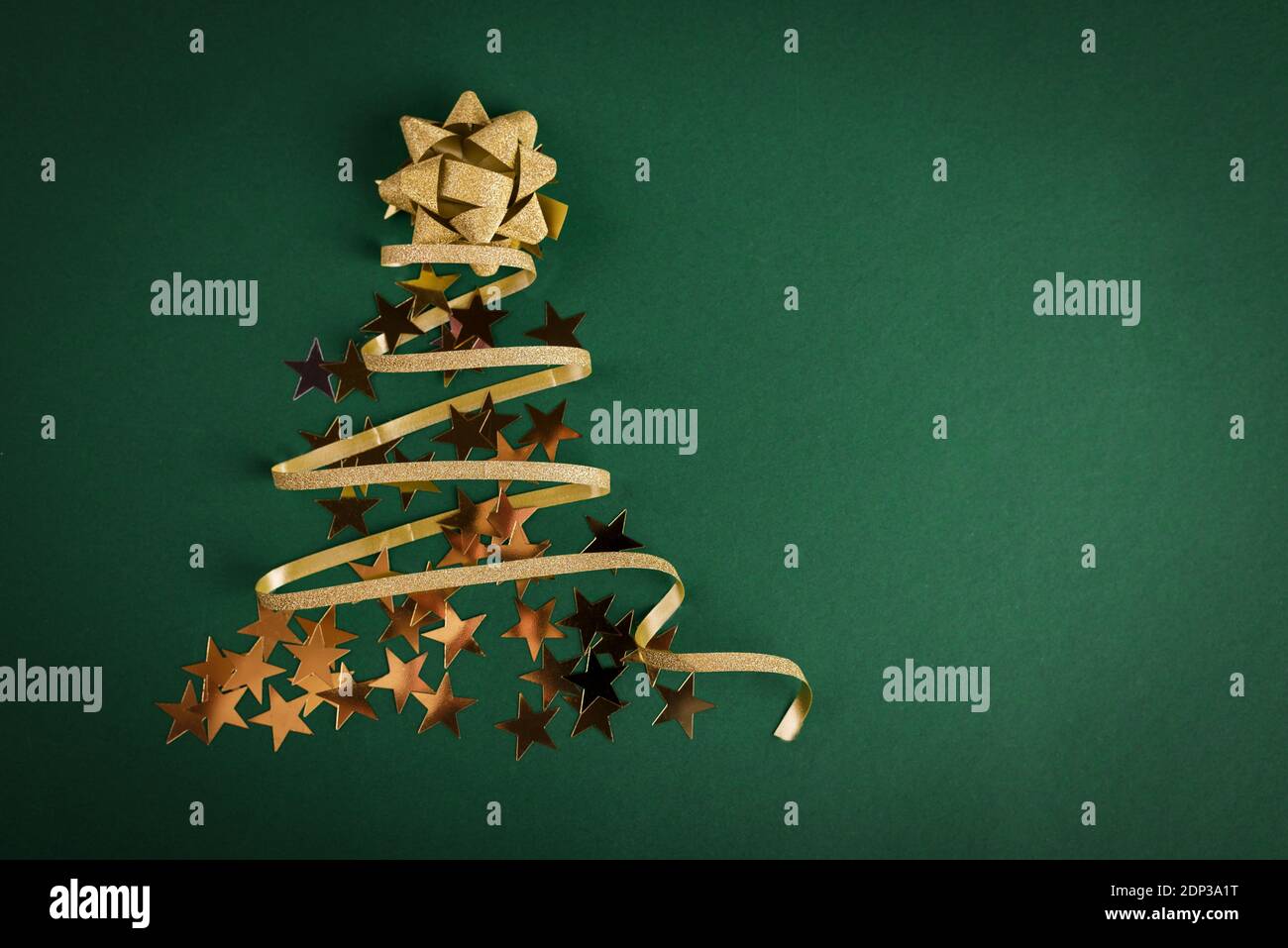 Albero di Natale realizzato con nastro d'oro su sfondo verde brillante. Buon Natale e felice anno nuovo sfondo festivo con spazio vuoto per il testo. Foto Stock
