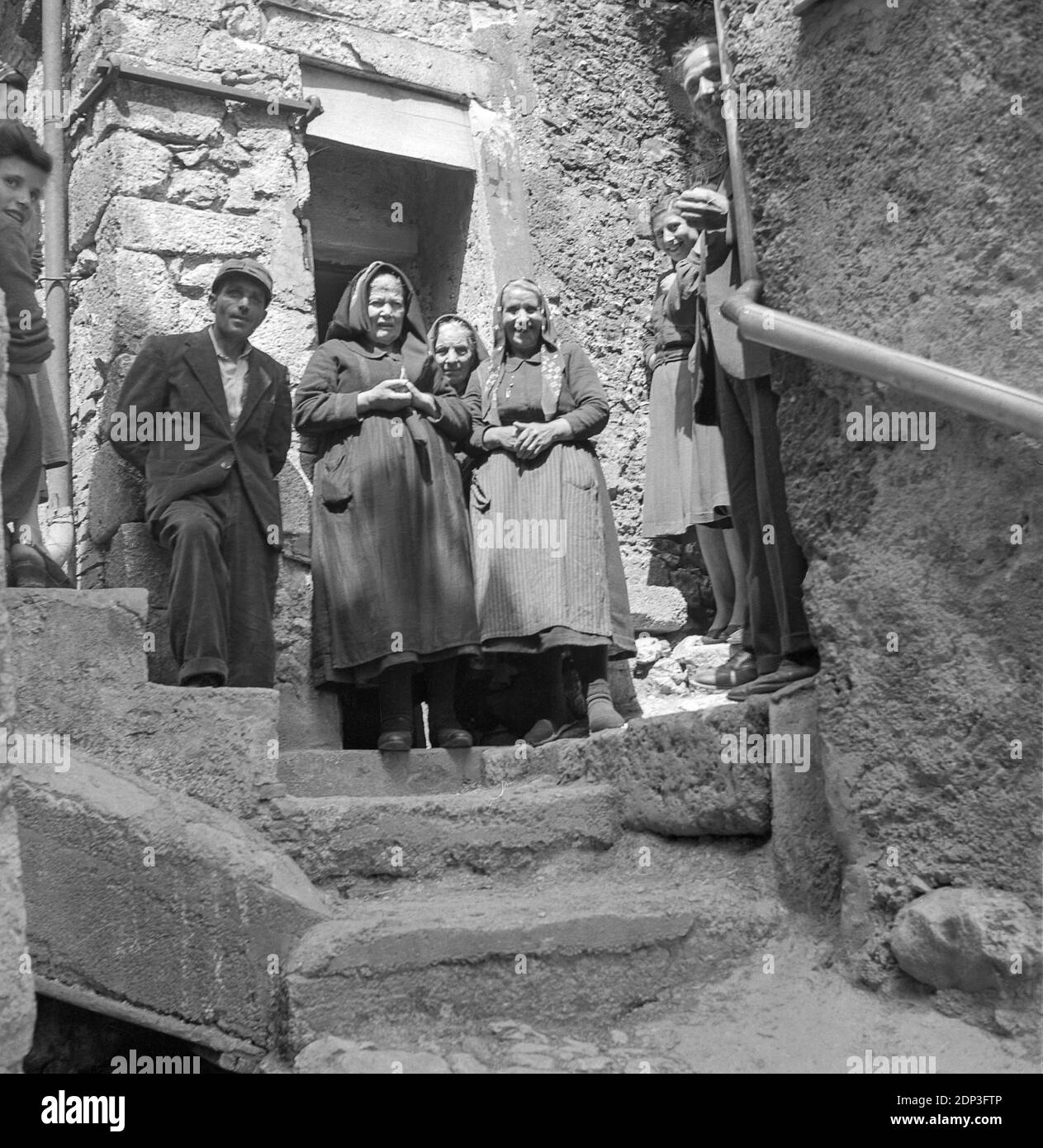 Locali che si levano in piedi sui gradini vecchi, 1951, LAquila, Italia Foto Stock