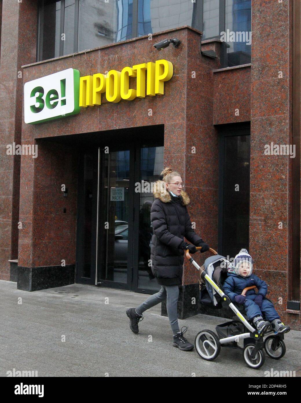Una donna che indossa una maschera facciale spinge un passeggino mentre  cammina oltre un 'Ze! (Logo del presidente ucraino Volodymyr Zelensky) in  centro Foto stock - Alamy