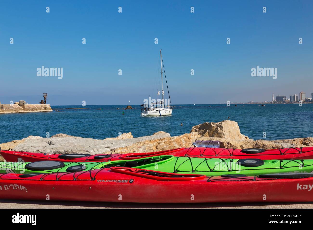 Kayak colorati e barca a vela che si dirigono verso il mare dal porto di Jaff, Israele Foto Stock