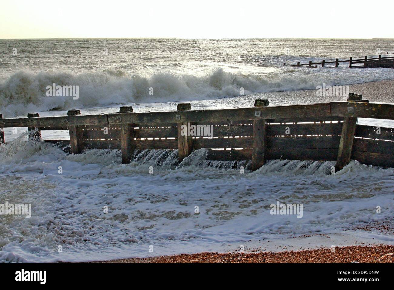 Vecchi groynes intemperie che proteggono la spiaggia di Pevensey Bay sulla costa meridionale dell'Inghilterra. Senza groynes la spiaggia soffrirebbe di erosione. Foto Stock