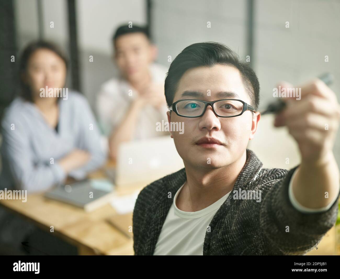 giovane uomo d'affari asiatico piccola impresa incontro con i colleghi disegno una curva sul vetro Foto Stock