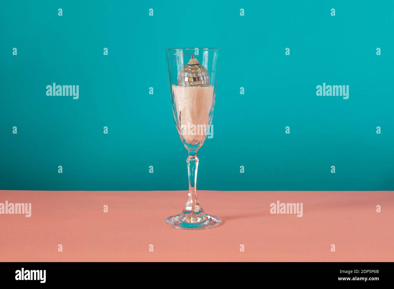 Disco palla all'interno del bicchiere su sfondo rosa e blu. Concetto invernale Foto Stock