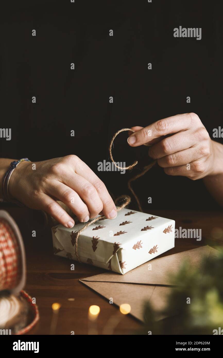 Una femmina che avvolge un regalo di Natale con carta riciclato di abete, burlap e foglie di abete Foto Stock