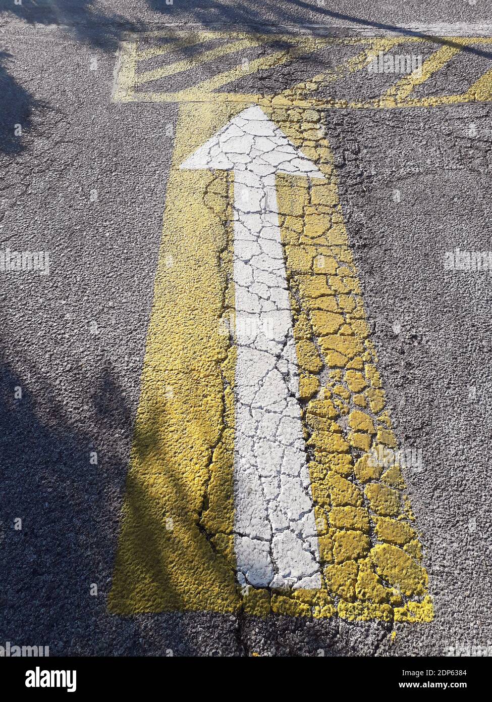 Freccia bianca su sfondo giallo su asfalto incrinato In un porto turistico in Grecia Foto Stock