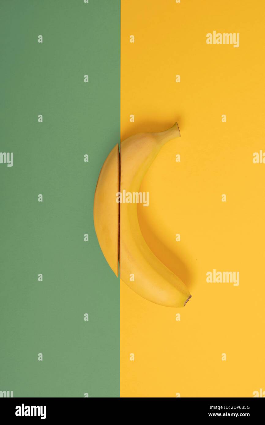 tagliare la banana su sfondo giallo verde Foto Stock