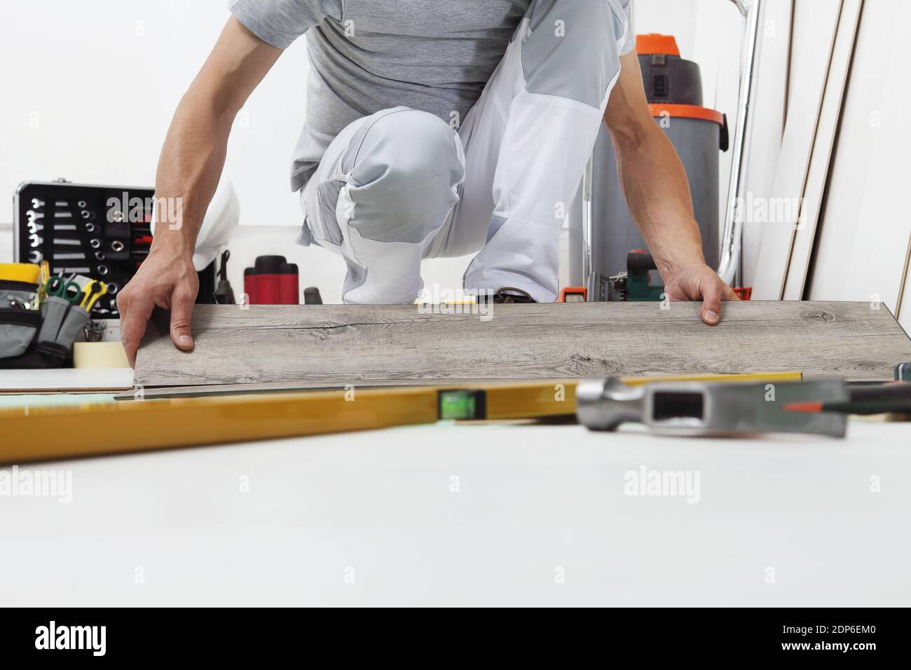 Mani di lavoro che installano pavimento in vinile laminato di legno. Ristrutturazione di case con pavimenti in legno. Foto Stock