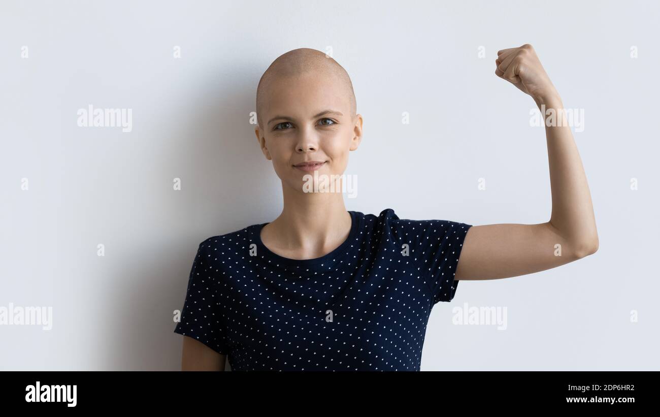 Potente donna malata con cancro guardando fotocamera che alza pugno Foto Stock