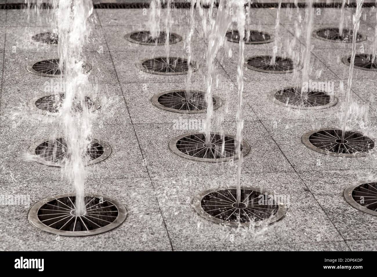 fontana di terra da un marciapiede di pietra, getti d'acqua sotto pressione  picchiano verso l'alto, spruzzi d'acqua lungo il marciapiede pedonale del  paesaggio della città da vicino Foto stock - Alamy