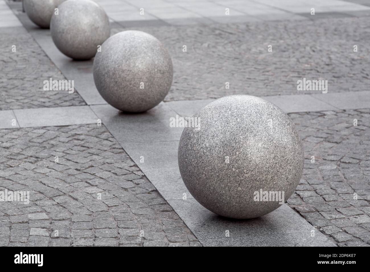 fila di palle di granito sul marciapiede pedonale lastricato con piastrelle di pietra, architettura urbana di città strada, nessuno. Foto Stock