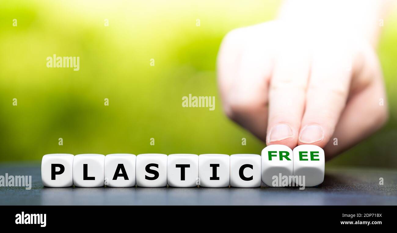 La mano gira i dadi e cambia l'espressione "plastica" in "senza plastica". Foto Stock