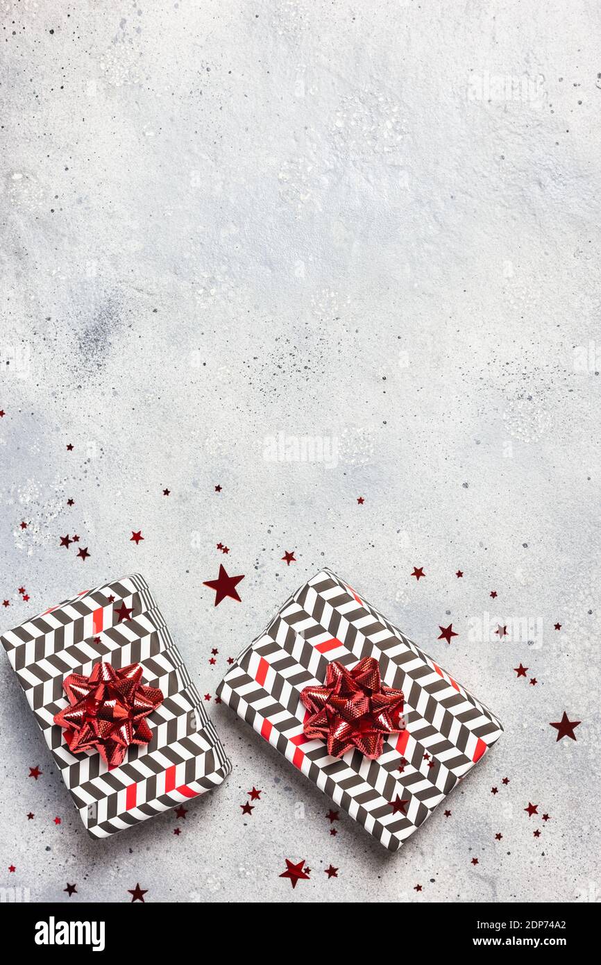 Composizione di Natale. Scatole regalo con decorazioni rosse su sfondo grigio. Natale, inverno, concetto di anno nuovo. Disposizione piatta, vista dall'alto, spazio per la copia. Foto Stock