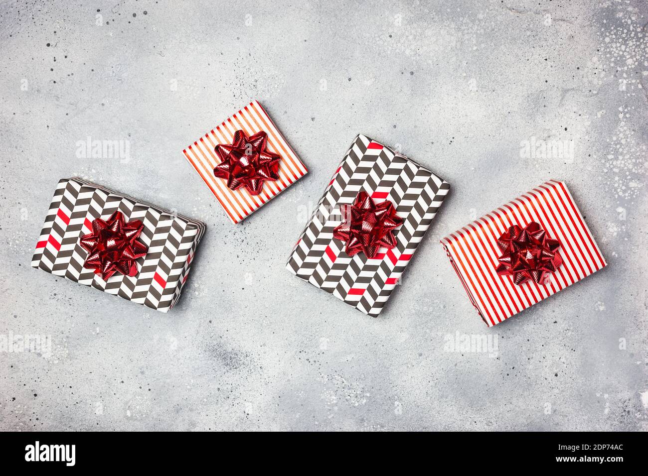 Composizione di Natale. Scatole regalo con decorazioni rosse su sfondo grigio. Natale, inverno, concetto di anno nuovo. Disposizione piatta, vista dall'alto, spazio per la copia. Foto Stock