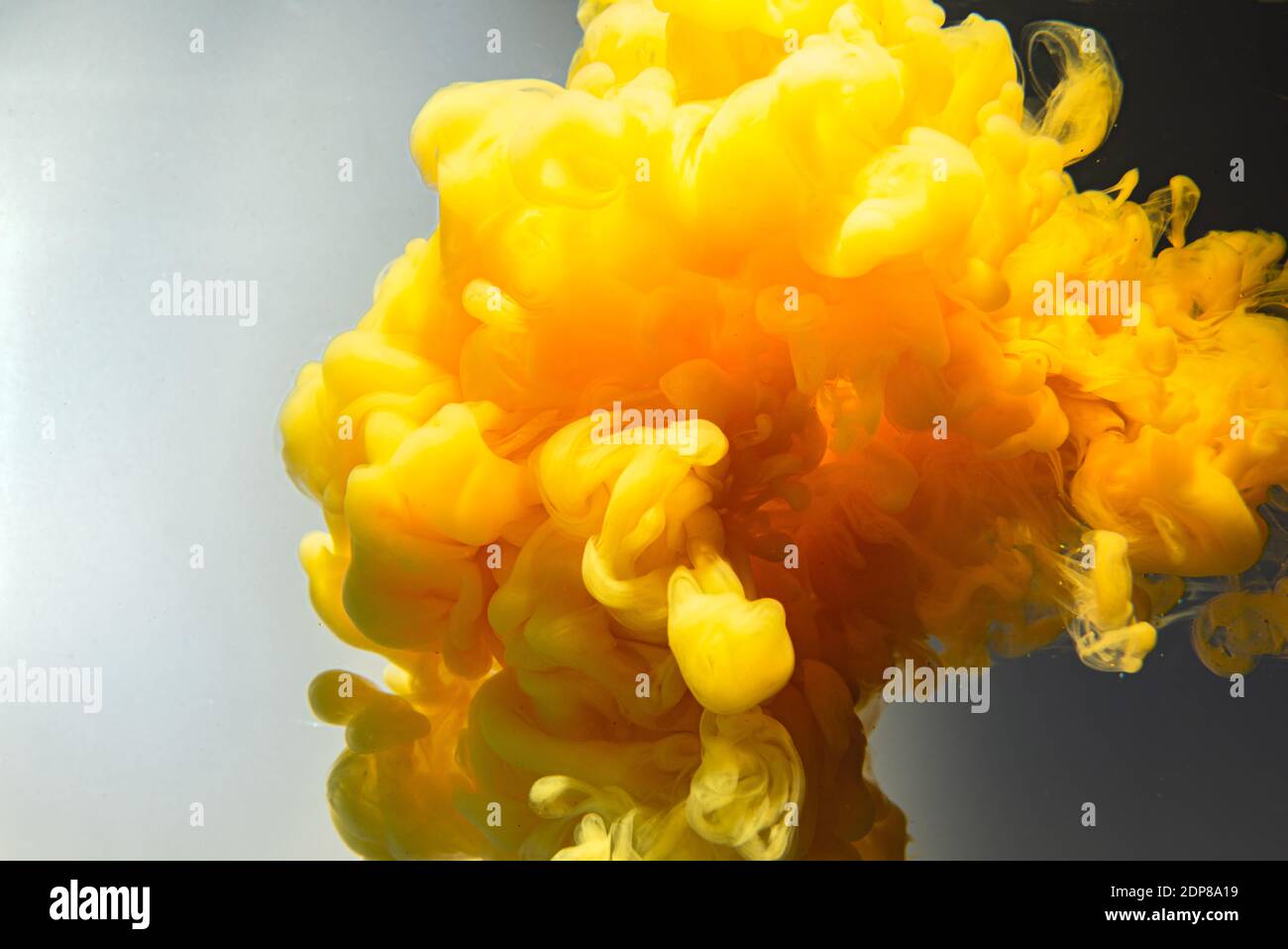 Gocce di colore in water.Yellow goccia di inchiostro che roteano sullo sfondo. Nuvola di inchiostro acrilico. Foto Stock