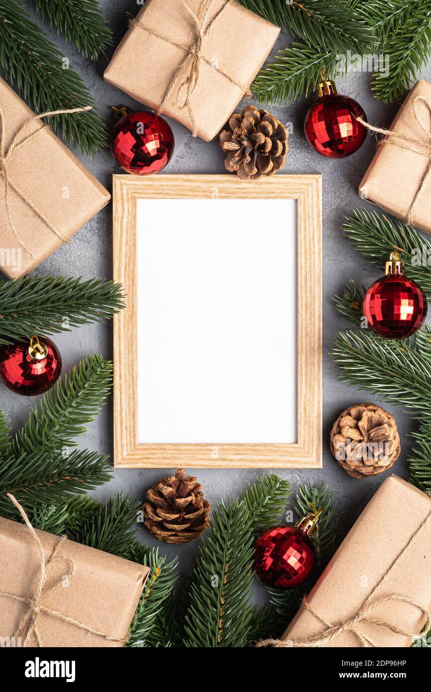 Natale vacanze composizione con immagine mockup cornice. Baubles rossi, regali e rami di abete. Foto Stock