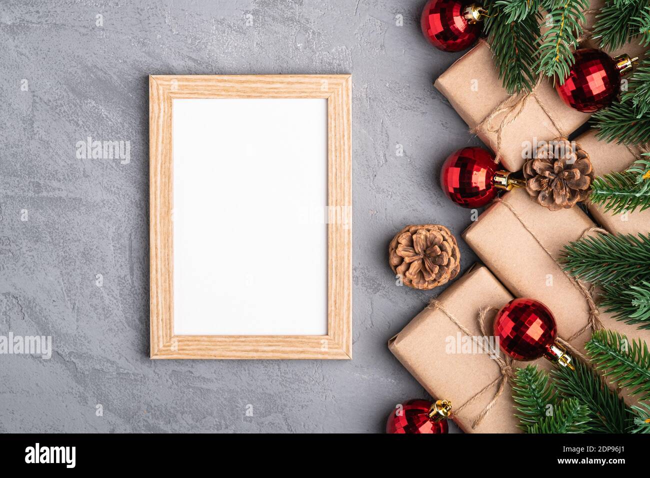 Natale vacanze composizione con immagine mockup cornice. Baubles rossi, regali e rami di abete. Foto Stock