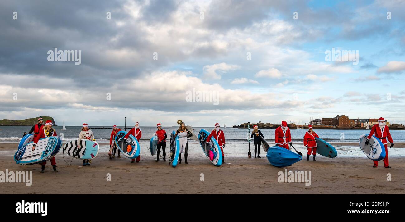 North Berwick, East Lothian, Scozia, Regno Unito, 19 dicembre 2020. Paddle imbarco Santas per la carità: Un'iniziativa locale della comunità da North Berwick News e opinioni chiamato 'Christmas Cheer' raccoglie oltre £5,000 fondi per le famiglie in bisogno. I paddle boarders vestiti in costumi di Santa posa per una foto sulla spiaggia Foto Stock