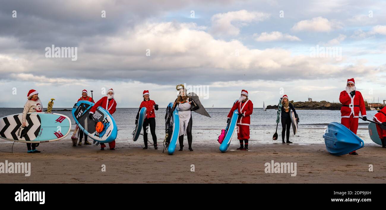 North Berwick, East Lothian, Scozia, Regno Unito, 19 dicembre 2020. Paddle imbarco Santas per la carità: Un'iniziativa locale della comunità da North Berwick News e opinioni chiamato 'Christmas Cheer' raccoglie oltre £5,000 fondi per le famiglie in bisogno. I paddle boarders vestiti in costumi di Santa posa per una foto sulla spiaggia Foto Stock
