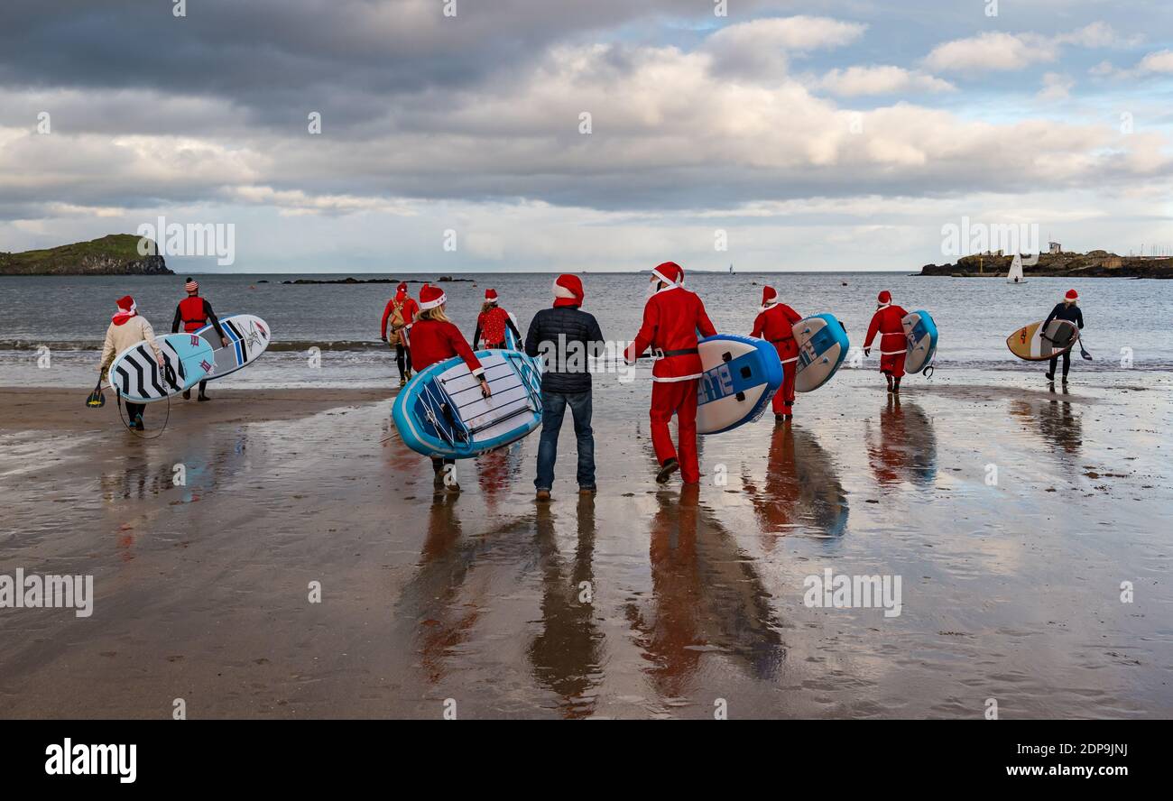 North Berwick, East Lothian, Scozia, Regno Unito, 19 dicembre 2020. Paddle imbarco Santas per la carità: Un'iniziativa locale della comunità da North Berwick News e opinioni chiamato 'Christmas Cheer' raccoglie oltre £5,000 fondi per le famiglie in bisogno. I paddle boarders vestiti in costumi di Santa entrano in acqua Foto Stock