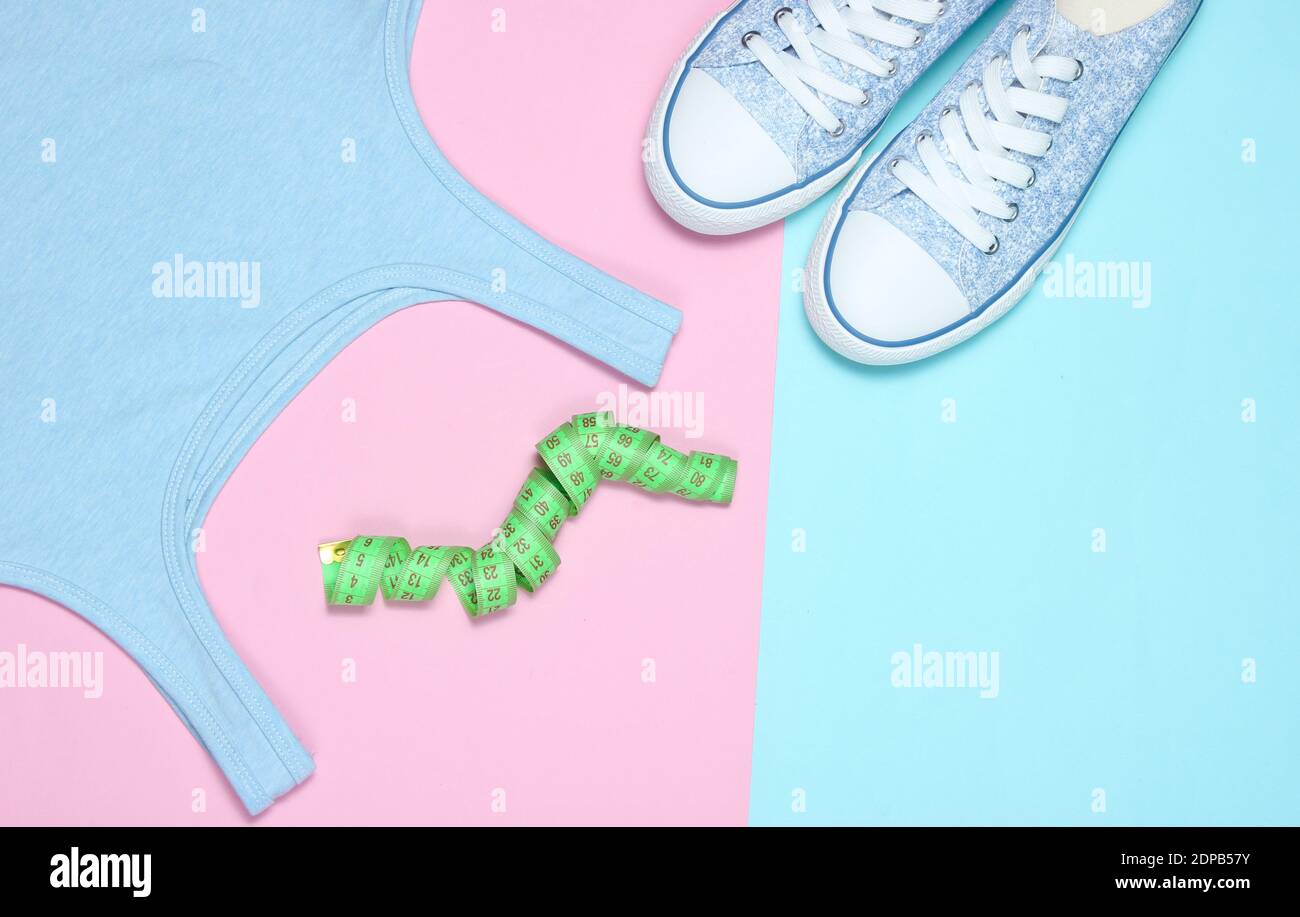 Concetto di fitness. T-shirt, righello, sneaker su sfondo pastello. Stile di posa piatto. Foto Stock