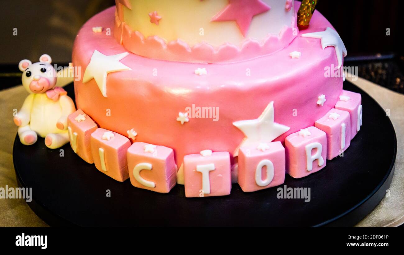 Un primo piano di una torta di compleanno rosa con stelle e. il nome di un vassoio sulla tabella Foto Stock