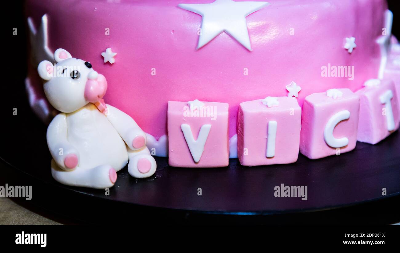 Un primo piano di una torta di compleanno rosa con stelle e. il nome su un vassoio Foto Stock
