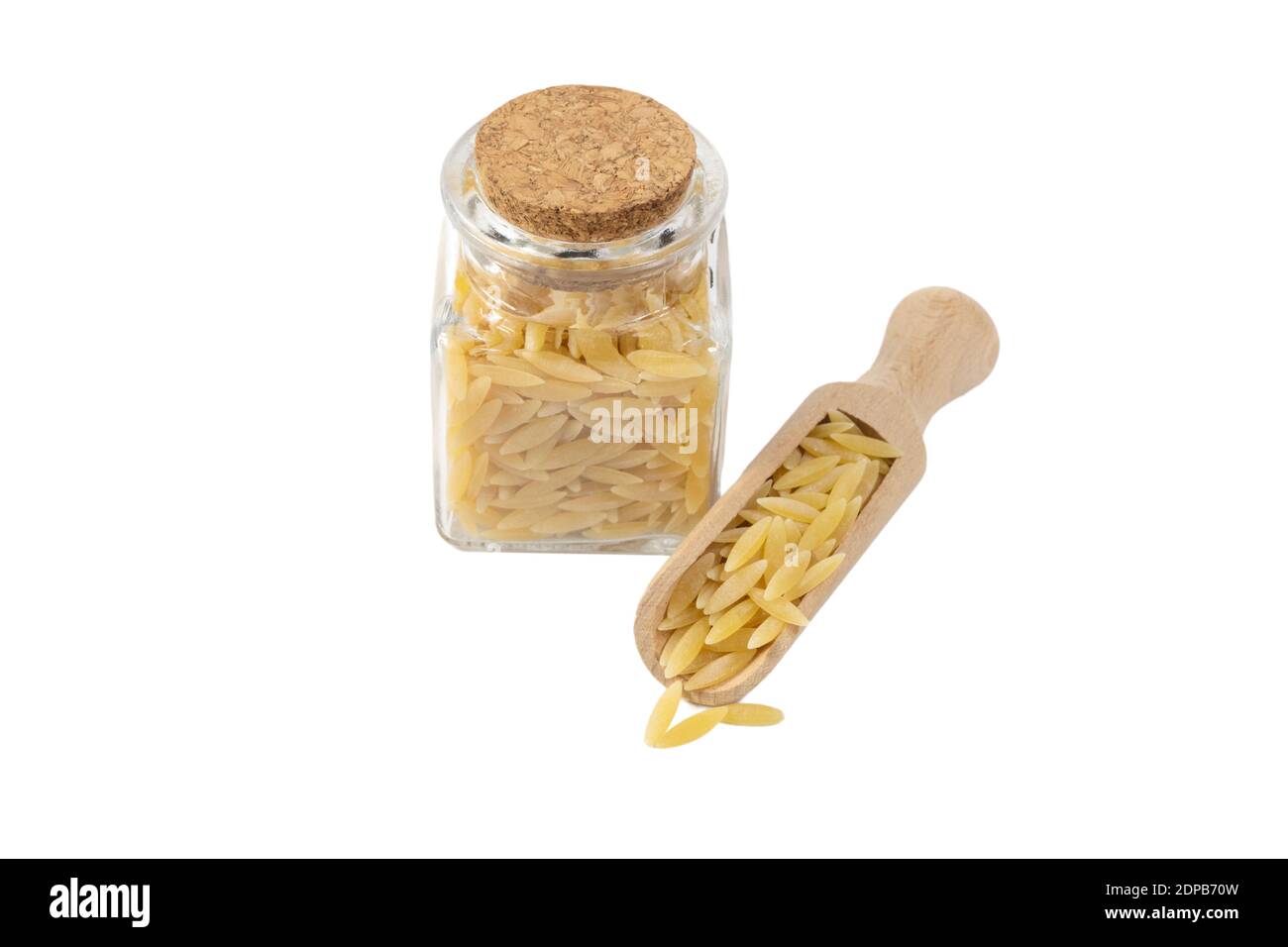 In Grecia chiamato kritharaki. In Italia si chiama Orzo. Pasta a forma di riso in paletta di legno e vaso di vetro su isolato su sfondo bianco. Tipo di pasta. Foo Foto Stock