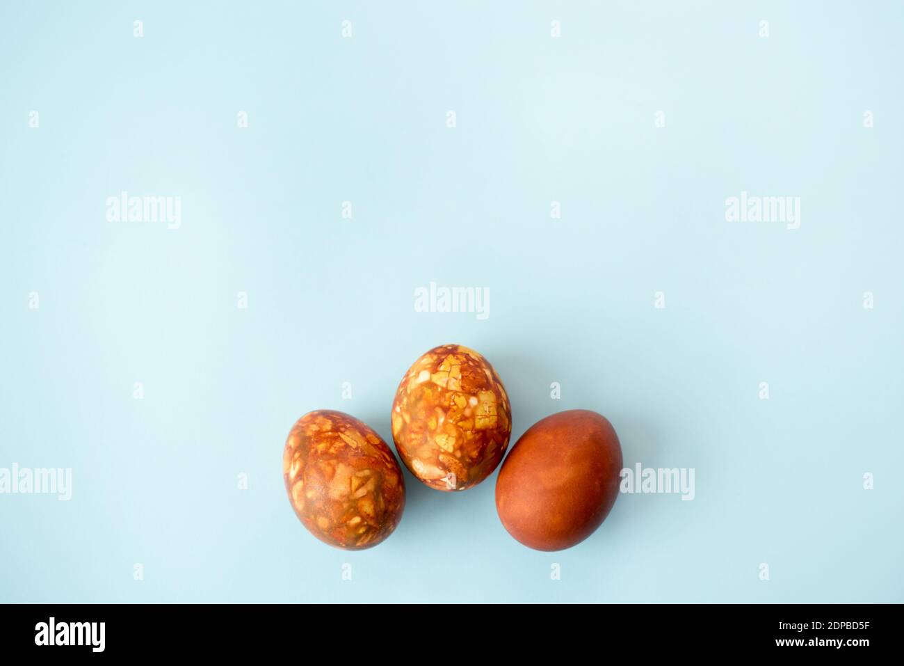 Tre uova di Pasqua marroni su sfondo blu con una copia spazio Foto Stock