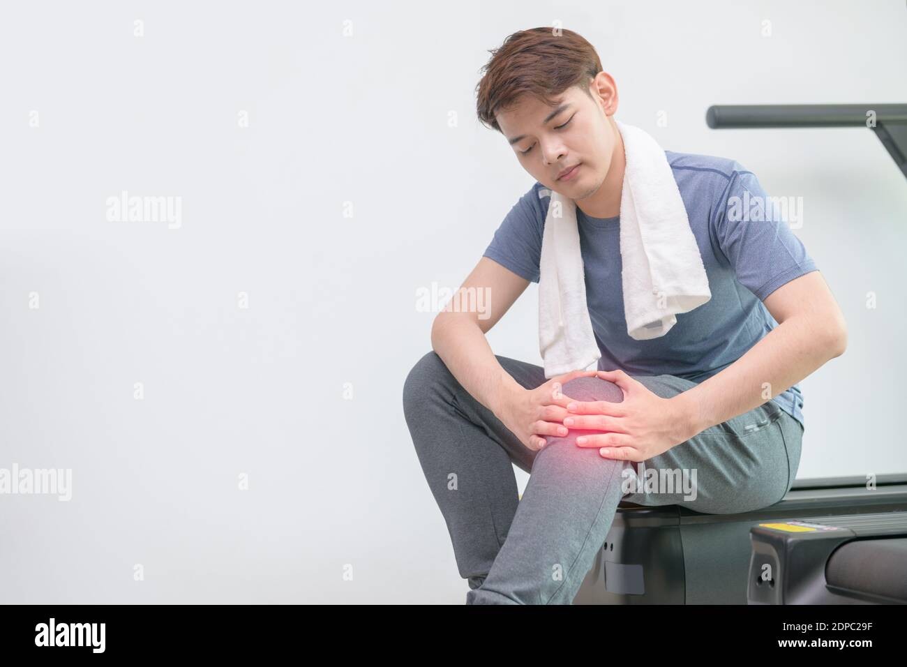Giovane uomo con dolore al ginocchio seduto in palestra Foto stock - Alamy