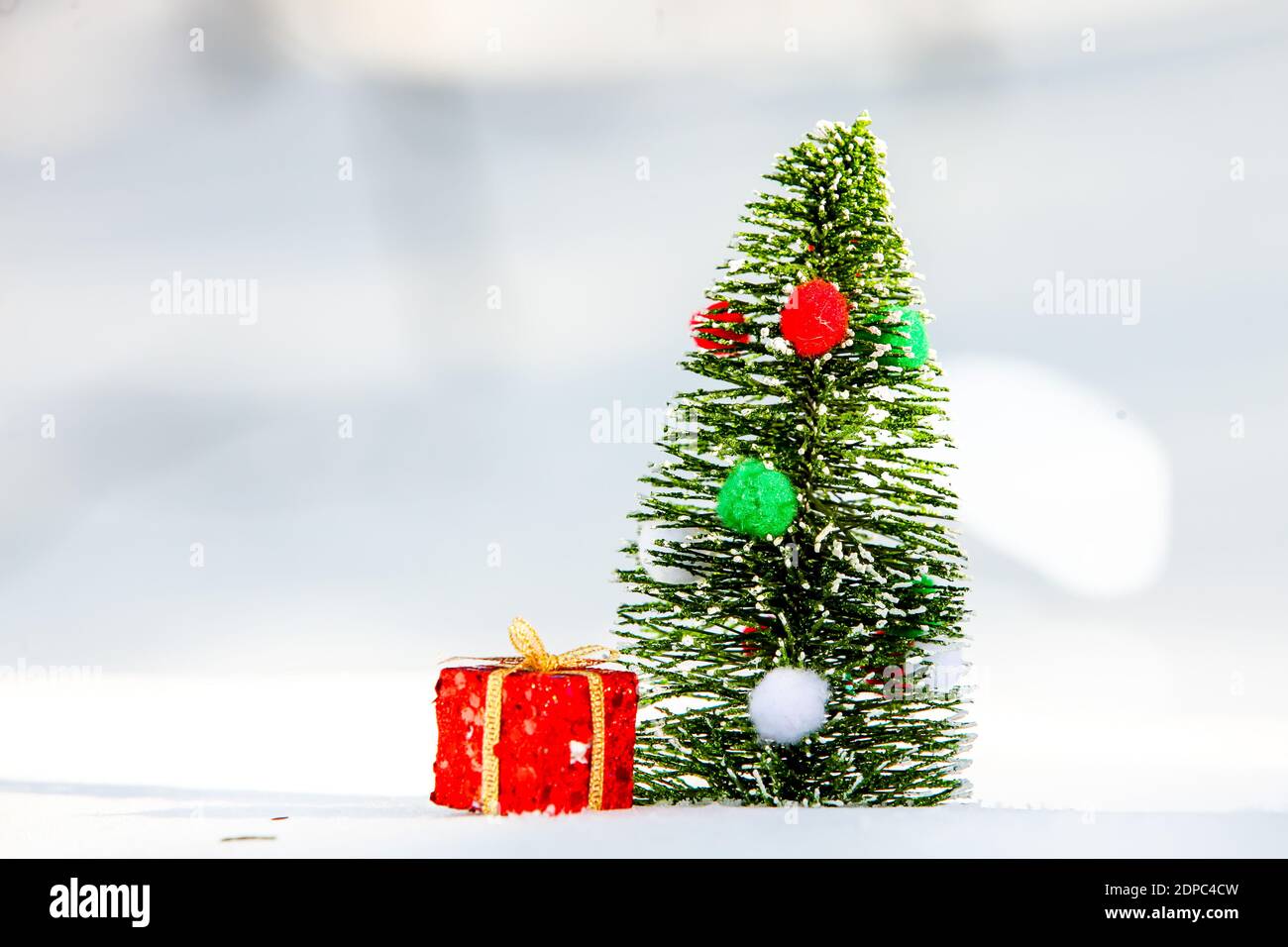 Albero di Natale sulla neve con scatola regalo rossa all'esterno Foto Stock