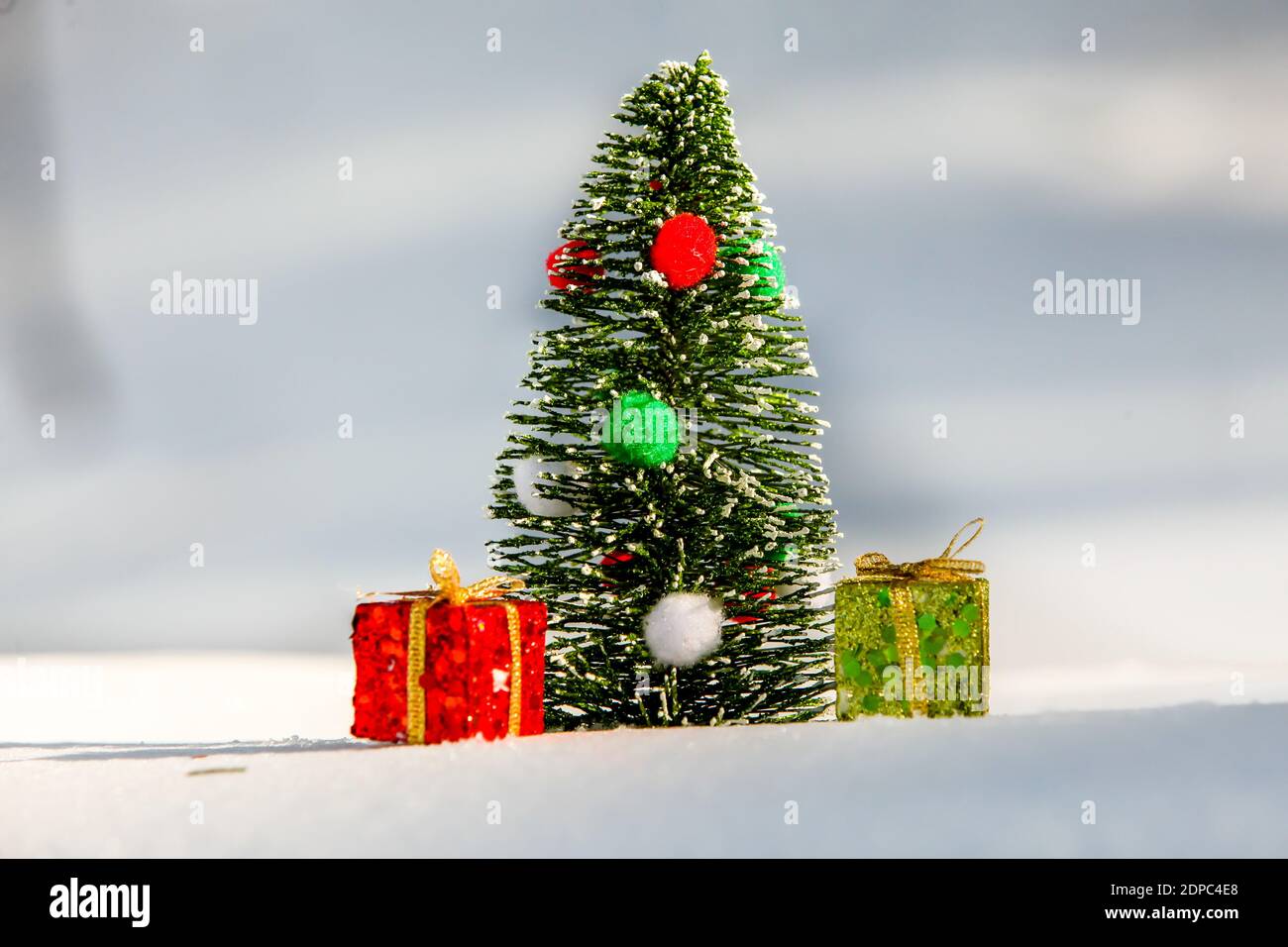 Albero di Natale sulla neve con scatola regalo rossa e verde esterno Foto Stock