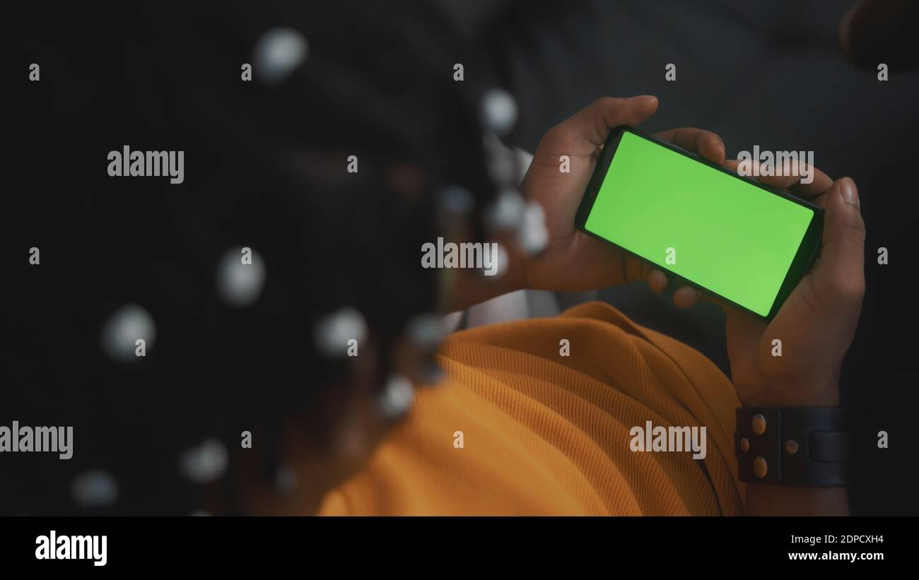 Uomo nero afroamericano che tiene smartphone con schermo verde e annuisce la testa. Foto di alta qualità Foto Stock