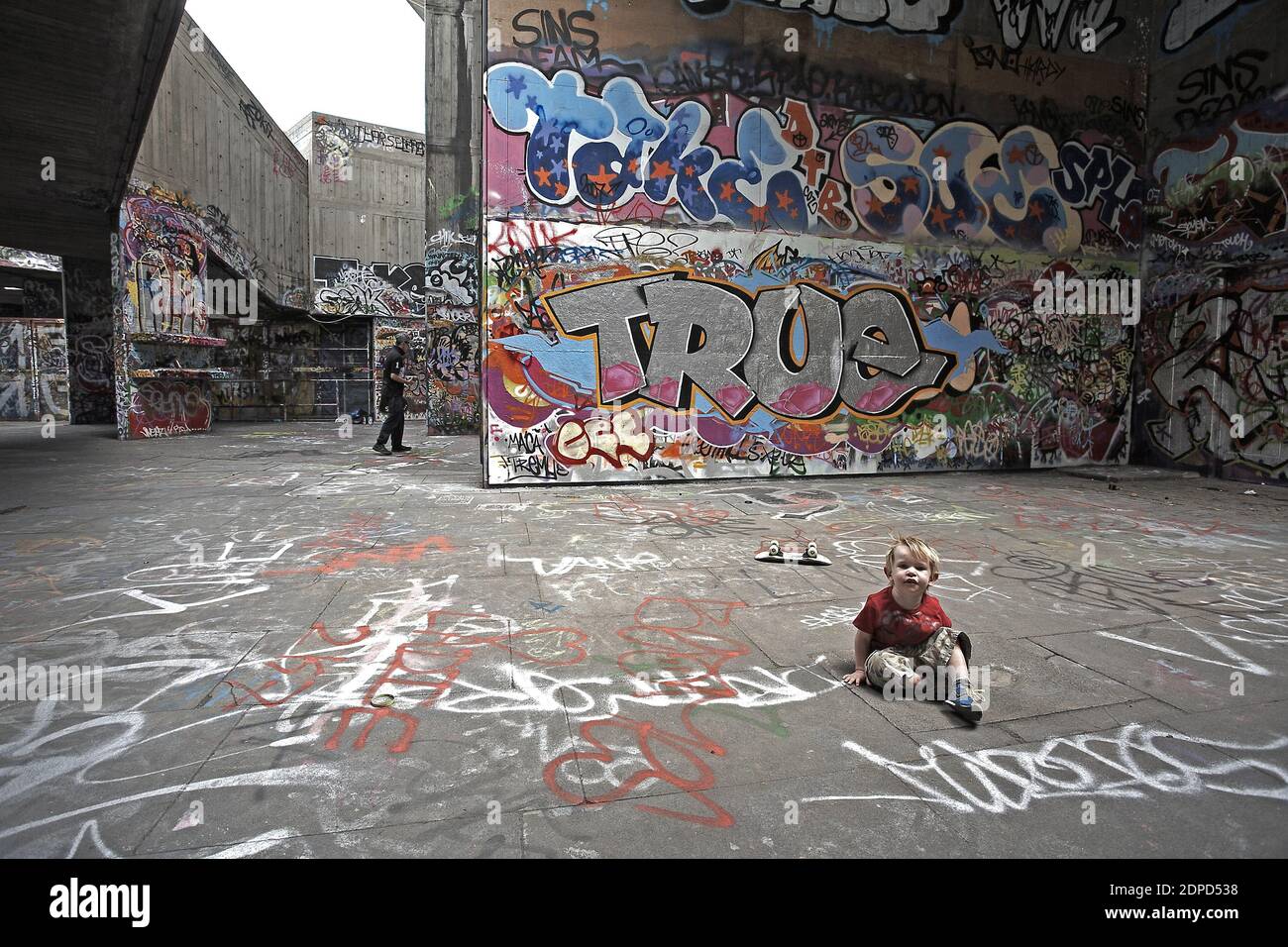 GRAN BRETAGNA / Londra / ragazzino con skatebord è seduto davanti ai graffiti. Foto Stock