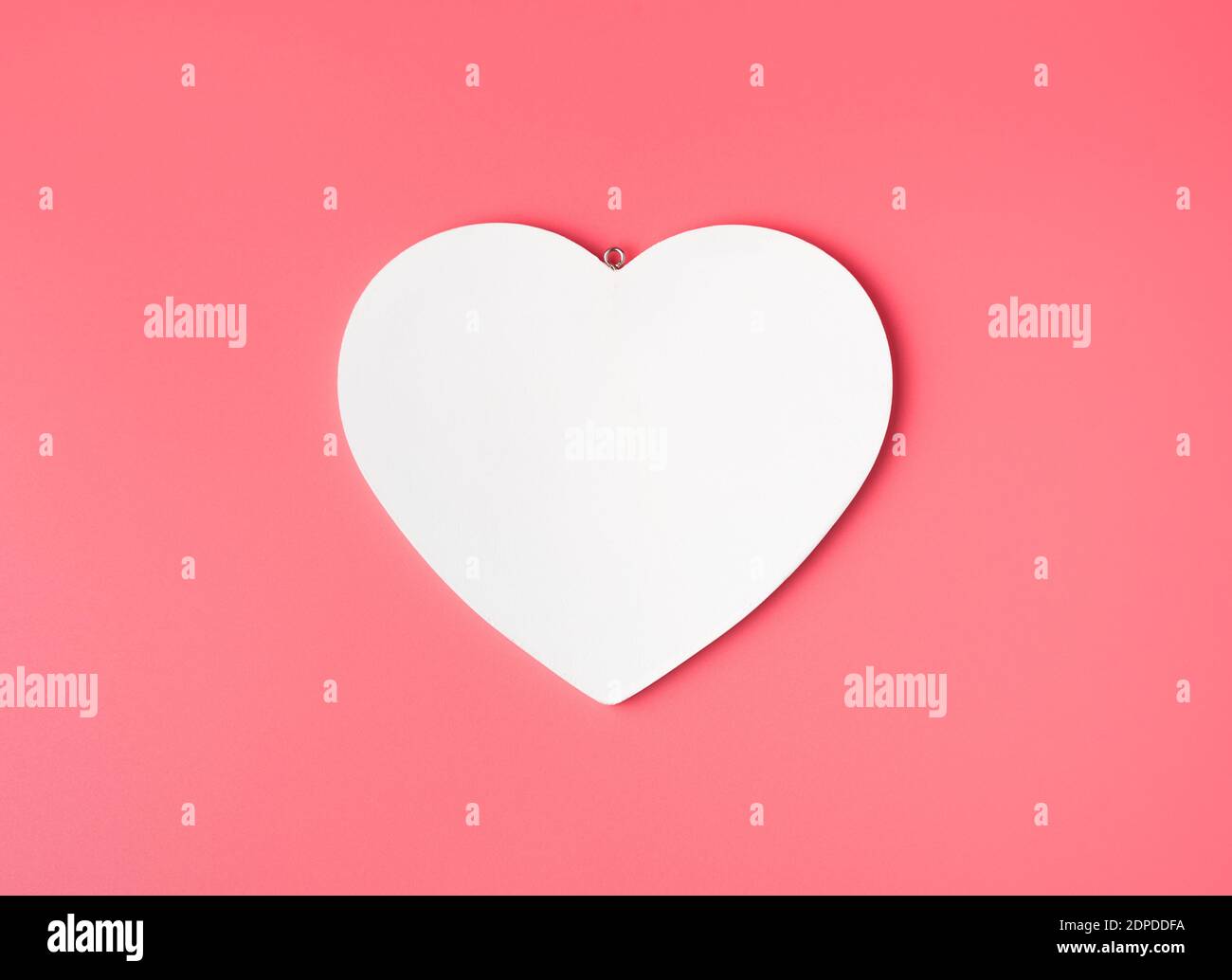 Il cuore è bianco su un delicato sfondo rosa chiaro. Foto Stock