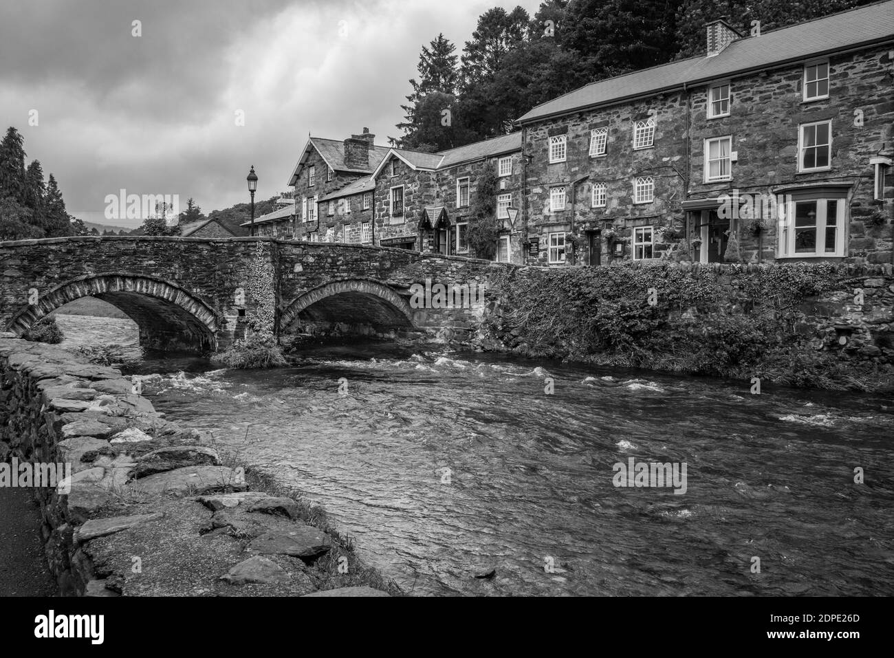 Bianco e nero del ponte sul fiume Colwyn nel pittoresco villaggio di Beddgelert, Galles Foto Stock