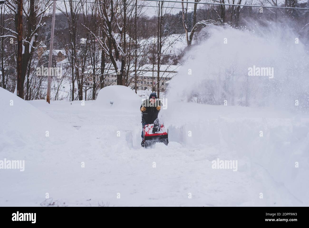 Un uomo nevicchia il suo vialetto nel bel mezzo dell'inverno. Foto Stock
