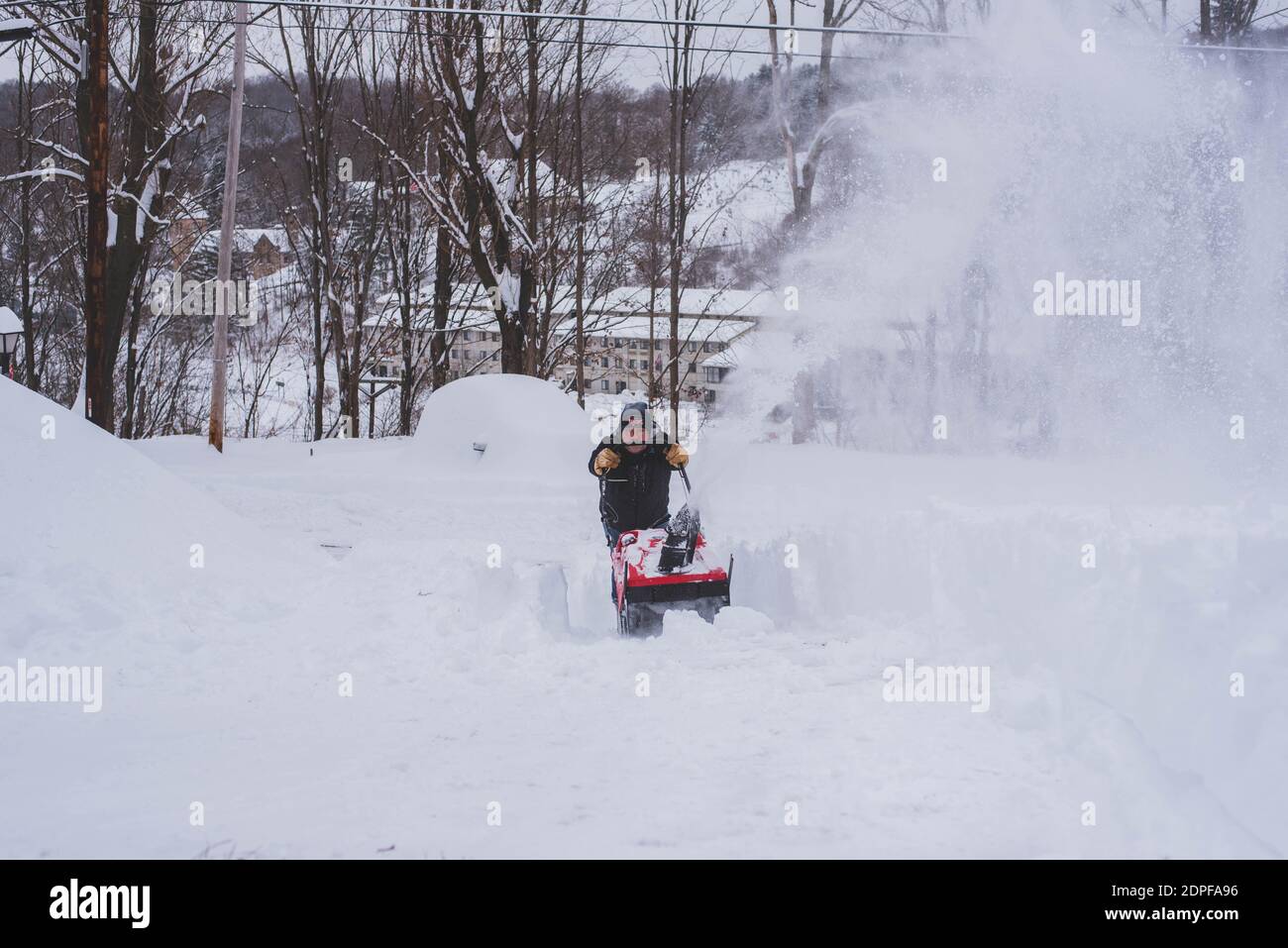 Un uomo nevicchia il suo vialetto nel bel mezzo dell'inverno. Foto Stock