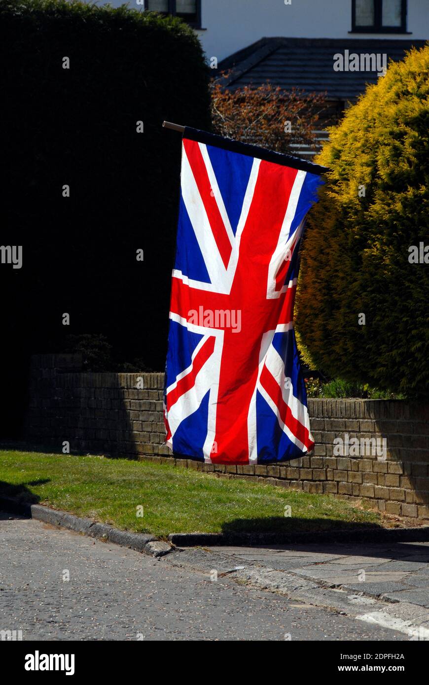 Grande bandiera di Unione retroilluminata in luce solare chiara fuori di una residenza domestica, in festa, Inghilterra Foto Stock