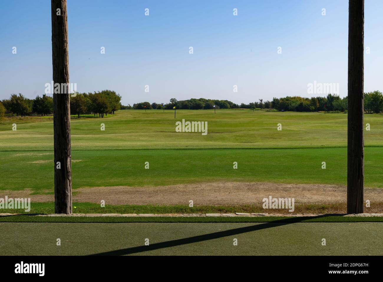 Vista che guarda fuori attraverso una scatola di golf campo pratica tee sul fairway ben falciato con diversi contrassegni colorati a distanze specificate. Foto Stock